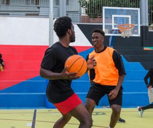 Group of friends playing street basketball on multicolored court